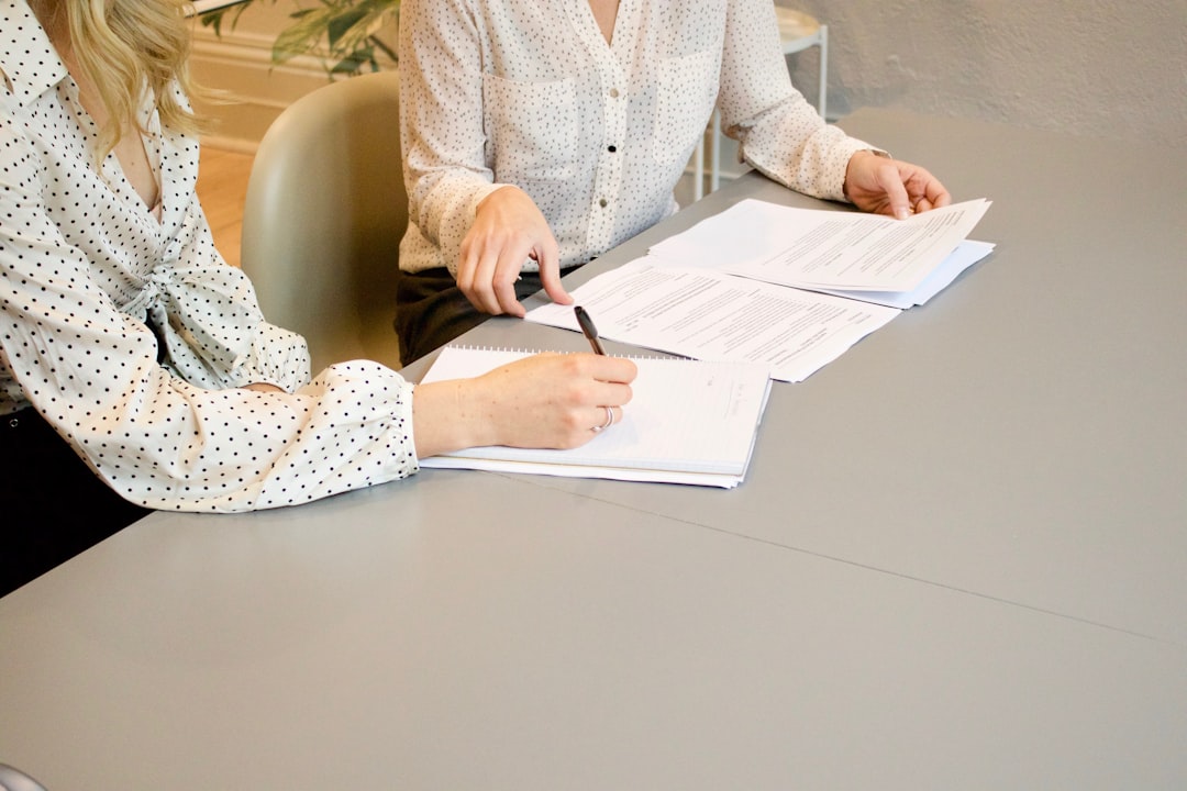 about-01 woman-signing-on-white-printer-paper-beside-woman-about-to-touch-the-documents-hjckknwcxxq